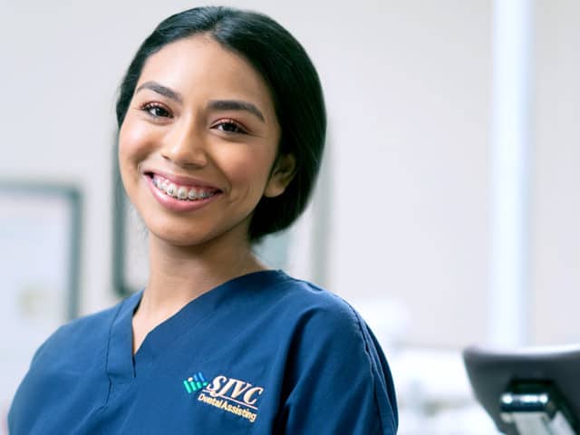 Young woman with braces in dark blue scrubs.