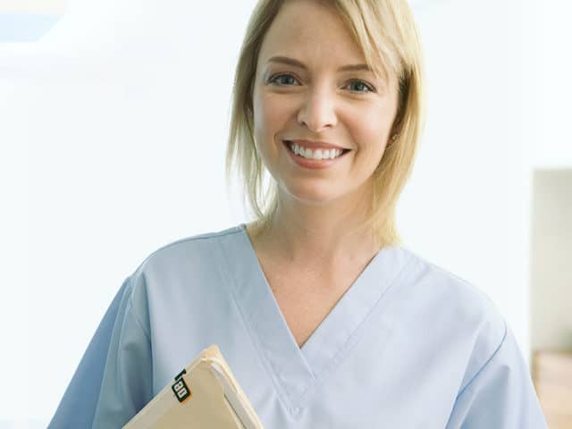 Female in scrubs with records folder.