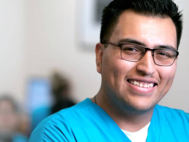 Young man in glasses and light blue scrubs.
