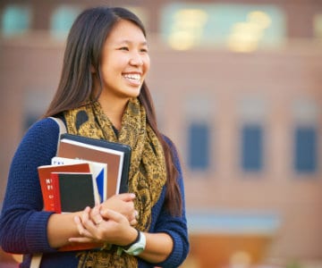 college student holding books and smiling