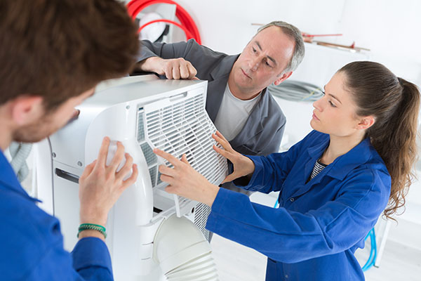 three technicians working on hvac unit