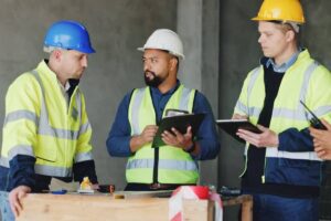 Man, checklist and group at construction site for meeting, review and planning for renovation project.