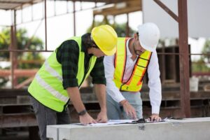 Two male construction managers working at construction site.