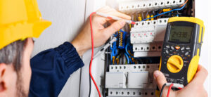 Electrician installing electric cable wires and fuse switch box. Multimeter in hands of electricians detail.
